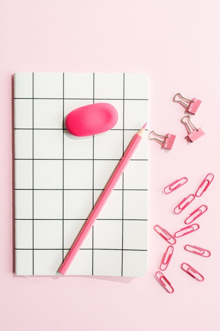 black and white notebook and pink pencil on pink background