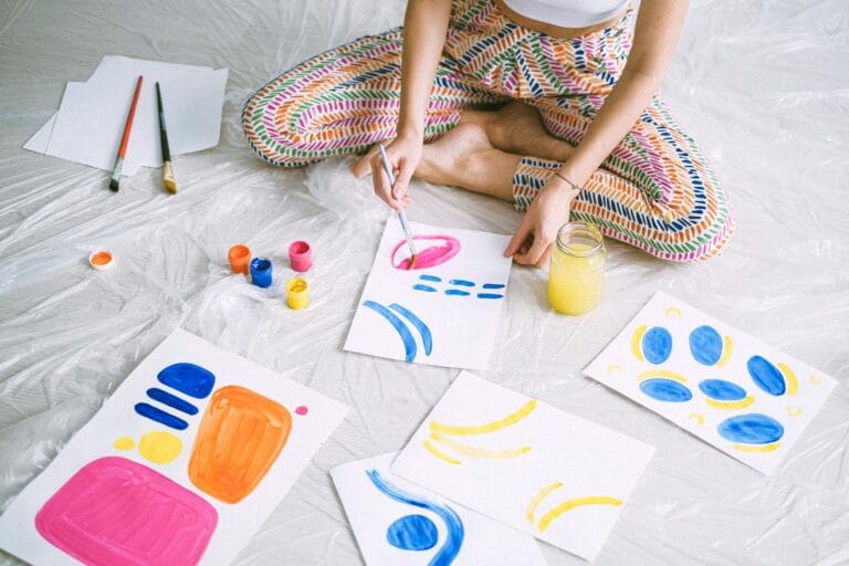 a woman painting with water colors on white paper